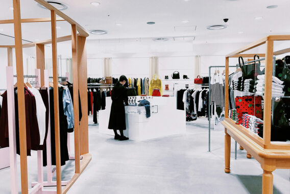 Overzicht van een lichte kledingwinkel met kledingrekken en displays.