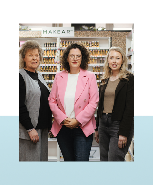 Drie vrouwen staan naast elkaar in een winkel met nagelverzorgingsproducten op de achtergrond.