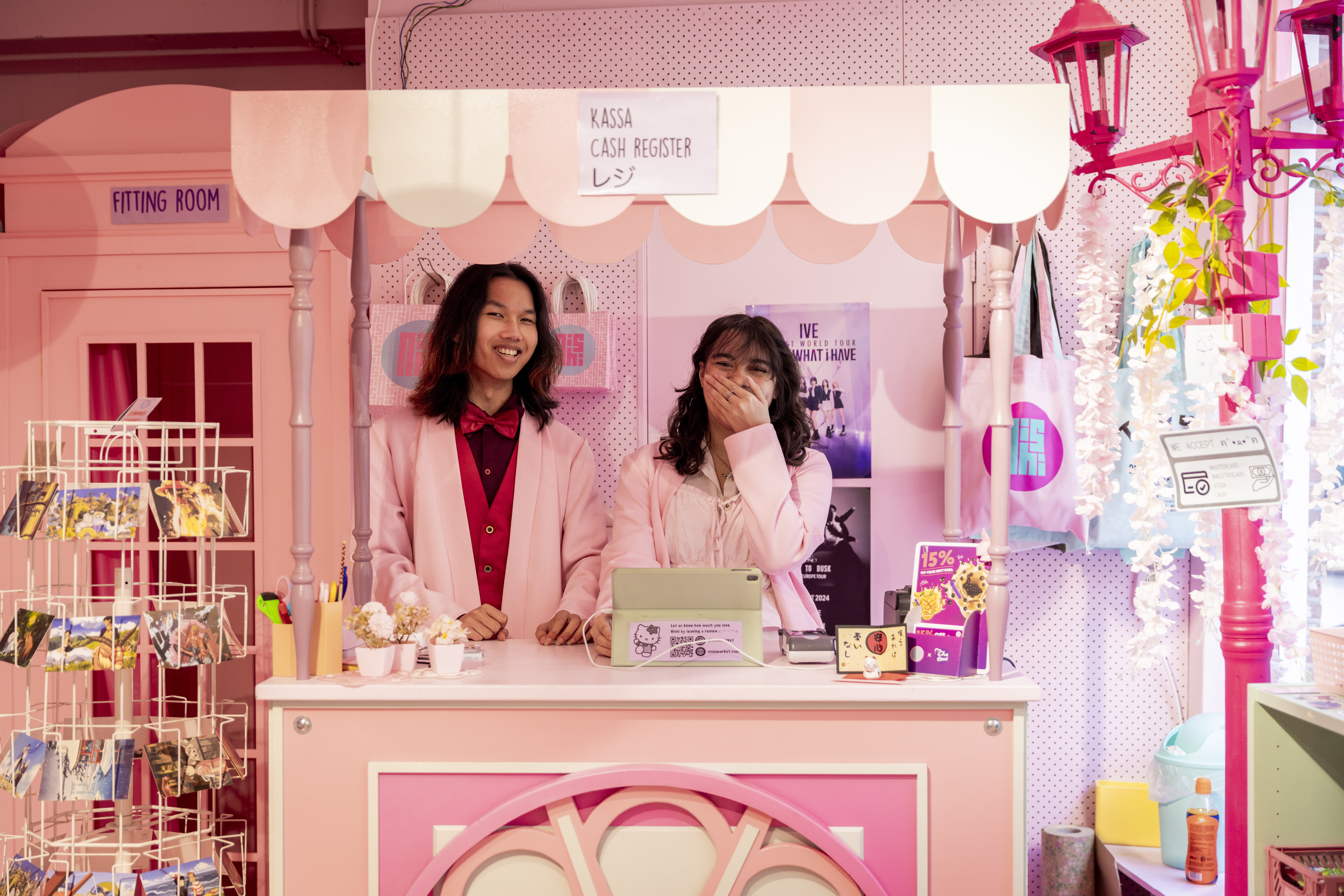 Foto: Twee medewerkers achter roze toonbank in winkel