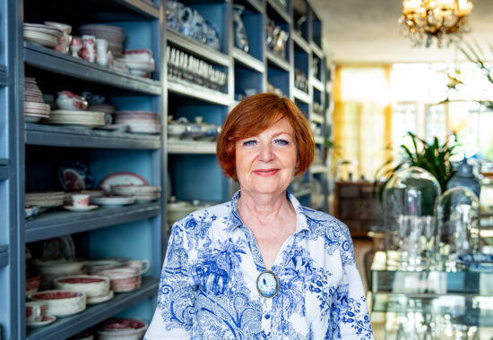 vrouw staat in een winkel met servies en glaswerk.