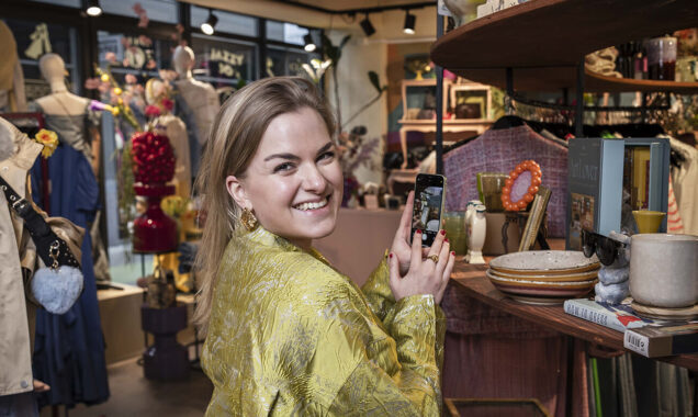 Vrouw staat in een winkel en maakt een foto van producten met haar telefoon.