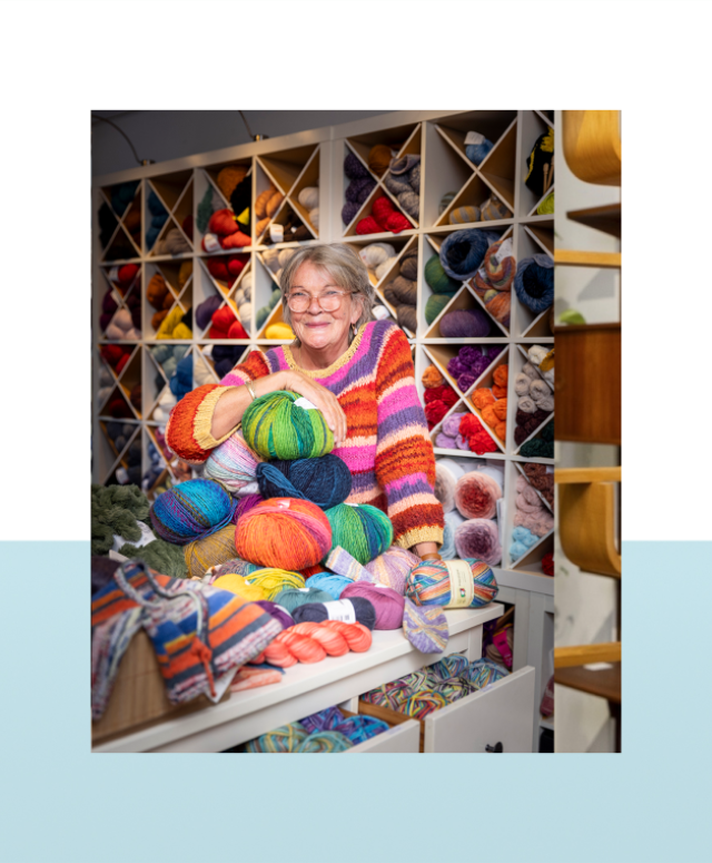 Vrouw met bril houdt kleurrijke bollen wol vast in een wolwinkel.