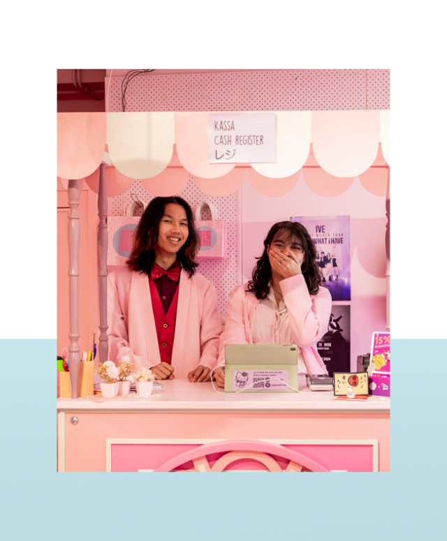 Twee medewerkers staan achter een roze toonbank in een winkel.