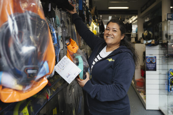 Vrouw pakt een product uit het schap in een duikwinkel.