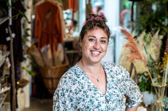 vrouw staat in een winkel met planten en decoratieve items.