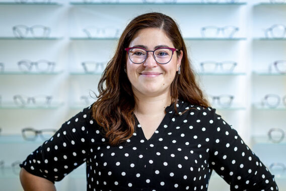 Vrouw staat voor een wand met brillen.