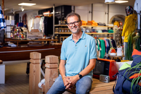 Man zit op een bankje in een winkel tussen kleding en accessoires.